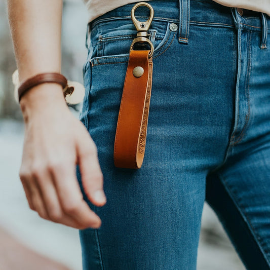 Close-up of a stylish leather keychain attached to a pair of jeans, showcasing a casual and effortless way to accessorize.