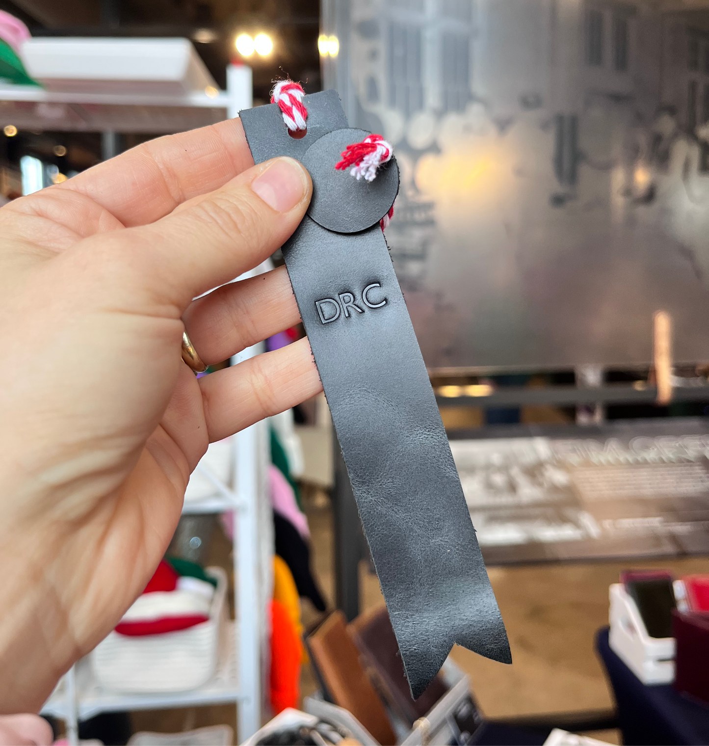 A person holding a handmade custom leather bookmark by NINE Leather & Watch.