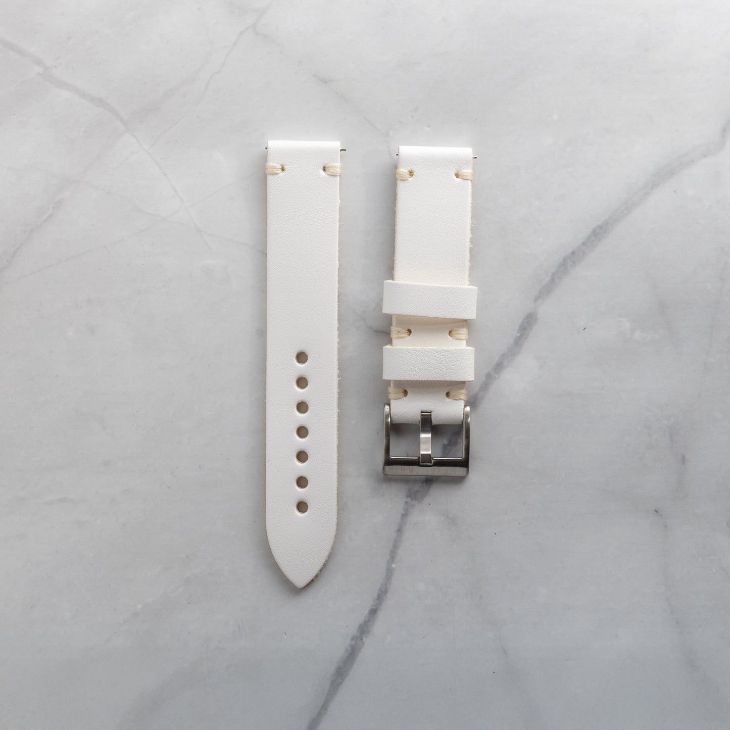 Meticulously fashioned white full-grain leather watch band with beige artisan hand-stitching, highlighting the supple texture and refined aesthetic of the material.