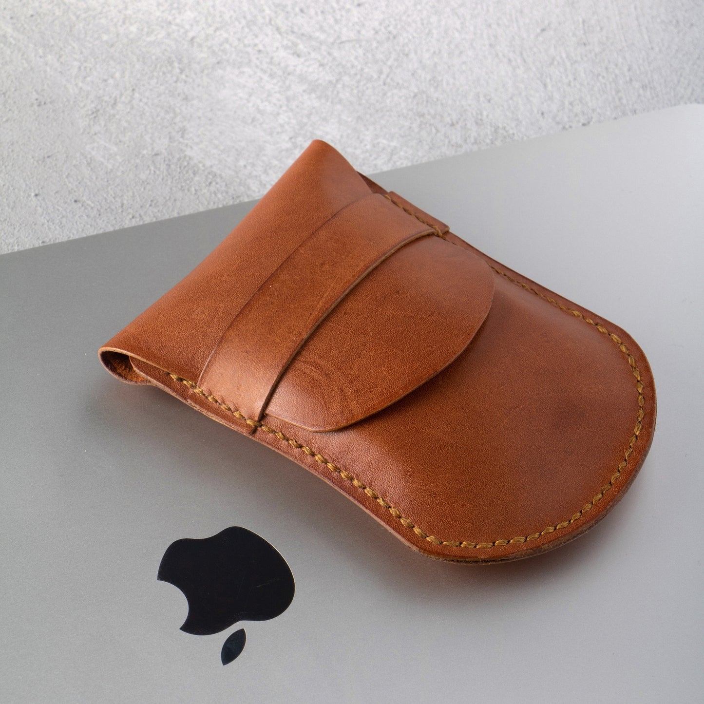 A brown leather case with an Apple Magic Mouse inside, showcasing its protective and stylish design.