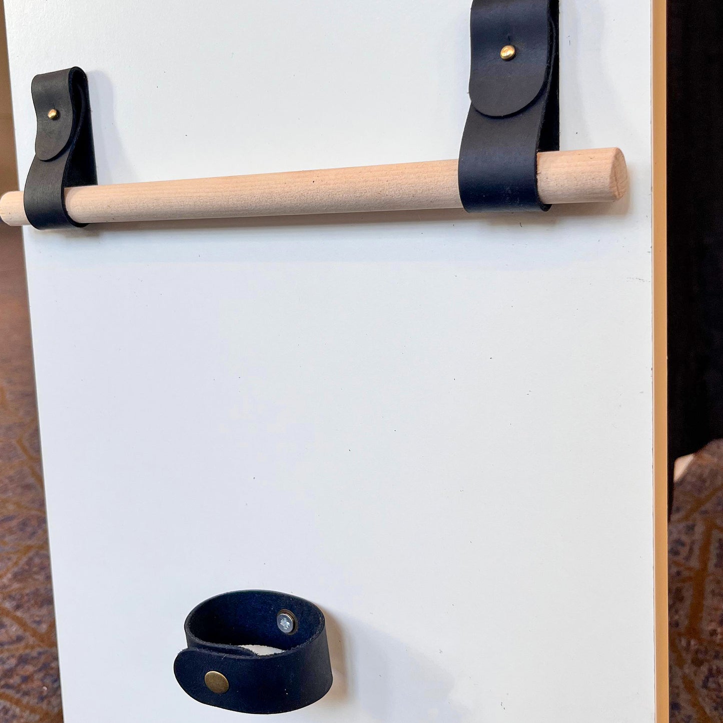 Perspective shot of black leather hardware for curtains or towels, custom-designed at the NINE workshop in Independence, MO.