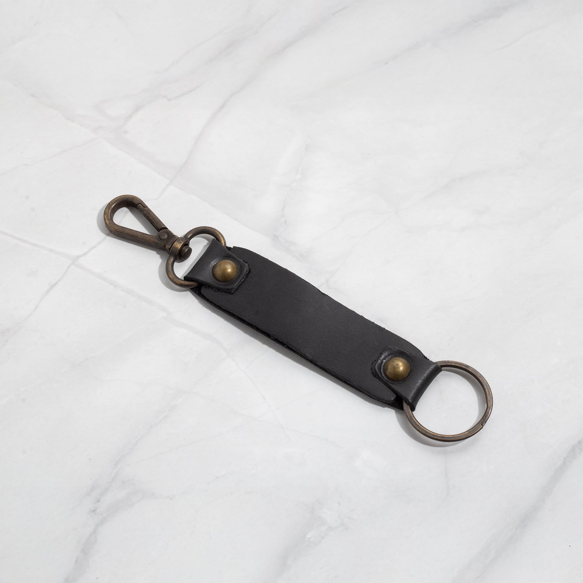 Classic black leather key strap featuring antique brass hardware, including a durable lobster claw clasp and split ring.