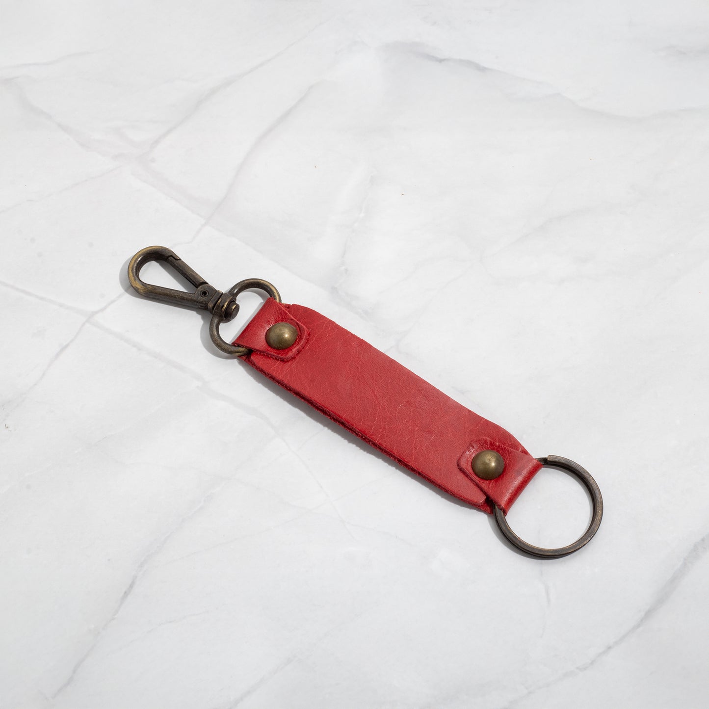 Vibrant red leather keychain strap connected to an antique brass swivel hook and key ring.