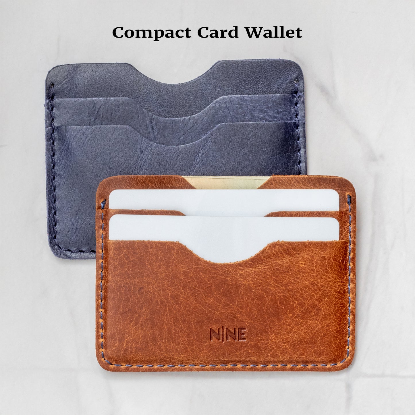 Two Compact Card Wallets. The rear wallet is Navy Blue (or dark indigo), and the front wallet is Tan, showing the four-pocket card design.