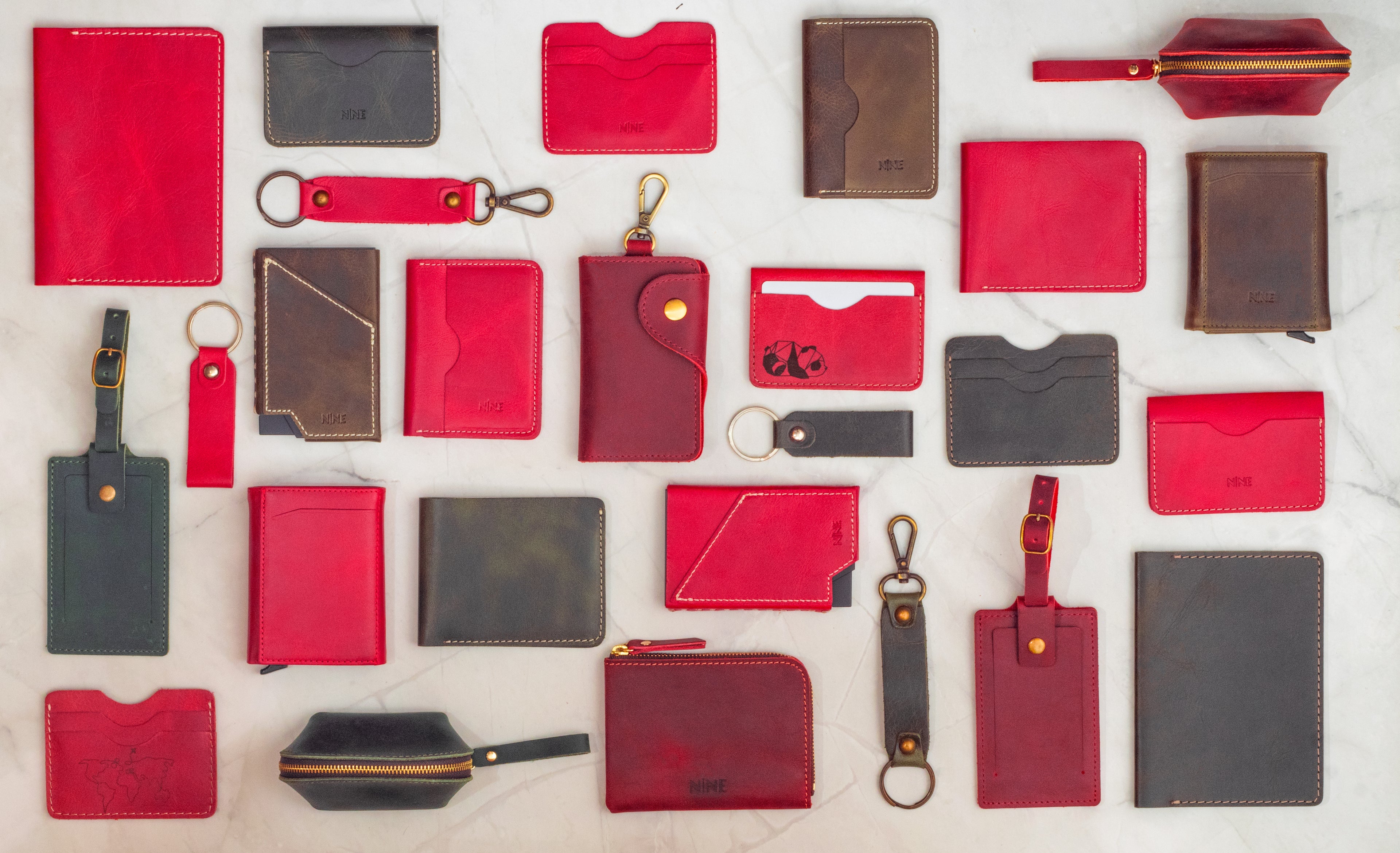 Collection of red and brown leather wallets, card holders, and keychains on a light gray background