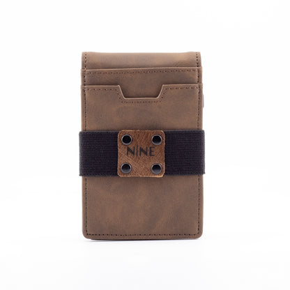 Front straight-on view of the upgraded brown genuine leather magnetic wallet, highlighting the secure black elastic money strap, riveted NINE badge, and premium stitching.