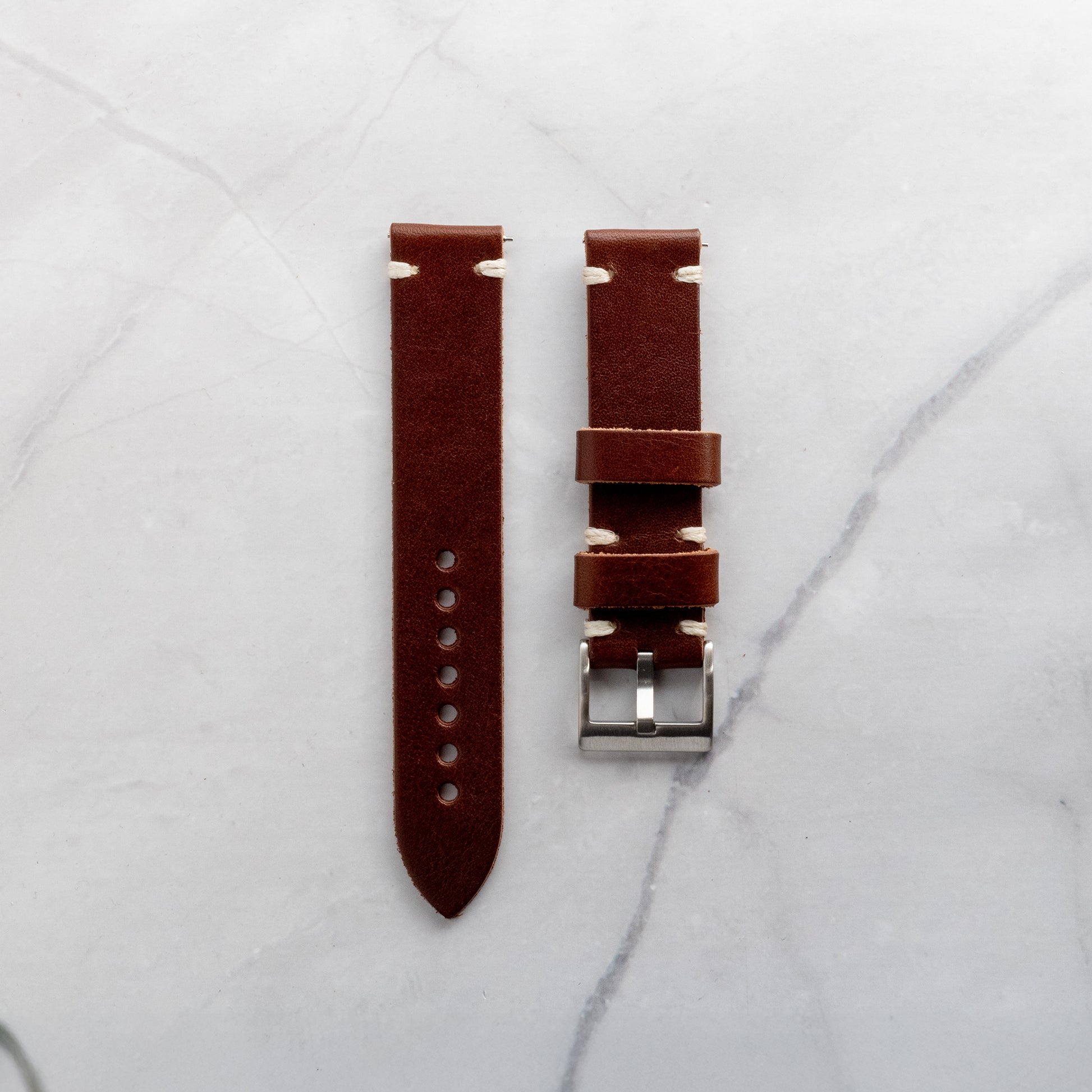 Handcrafted dark brown leather watch strap made from premium full-grain hide with cream-colored minimalist stitching and a durable stainless steel buckle.