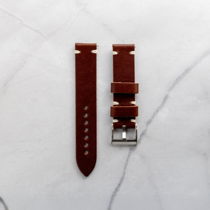 Handcrafted dark brown leather watch strap made from premium full-grain hide with cream-colored minimalist stitching and a durable stainless steel buckle.