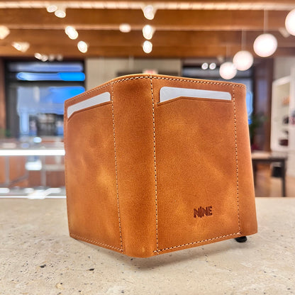 A tan brown NINE Leather & Watch Mechanical Wallet fully opened, showcasing its multiple card slots, dedicated cash compartment, and the brand's logo discreetly embossed on the leather.