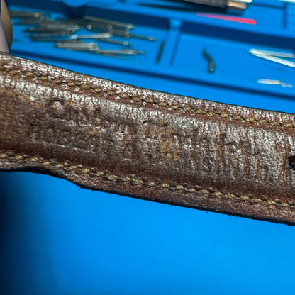 Close-up of the back of a custom leather watch strap showing the previous owner's stamped name, adding unique provenance to the vintage watch.