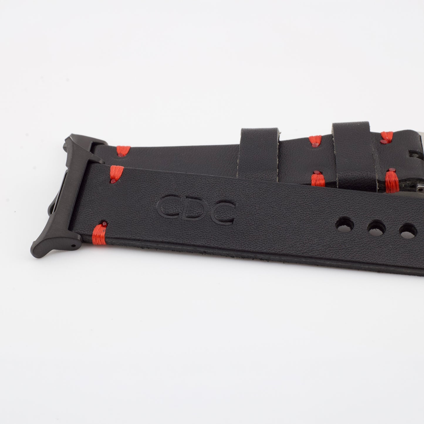Close-up of a handcrafted black leather watch strap showing custom red stitching, a stamped CDC logo, and a matte black metal connector.