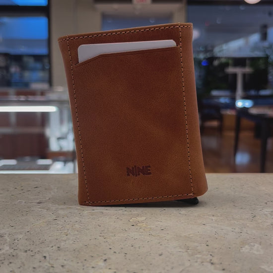 A close-up video showcasing the quick-access mechanism of a Nine Leather & Watch Mechanical Wallet, ejecting cards with a push of a button.