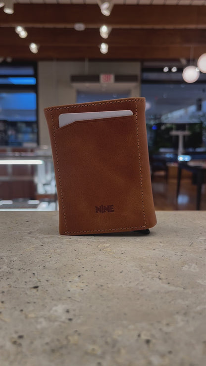 A close-up video showcasing the quick-access mechanism of a Nine Leather & Watch Mechanical Wallet, ejecting cards with a push of a button.