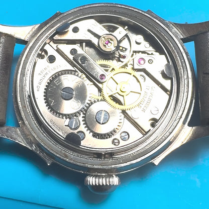 Close-up video demonstrating a vintage 1940s Minerva mechanical watch. The footage highlights the active 17-jewel Swiss movement ticking, a watchmaker manually securing the stainless steel case back, and a final presentation of the authentic patina dial and custom leather strap.