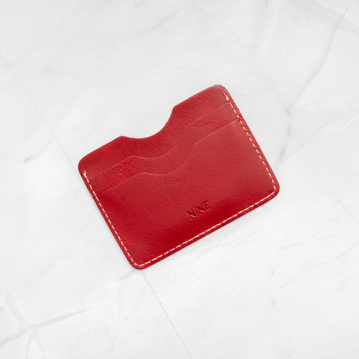 Red Full-Grain Leather Compact Card Wallet, highlighting the durable stitching and minimalist form.