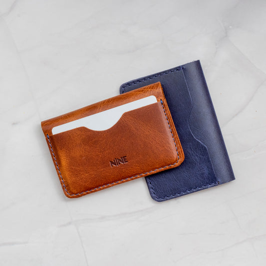 Two Minimalist Bifold Wallets in Tan and Blue Full-Grain Leather, illustrating the compact, slim profile.