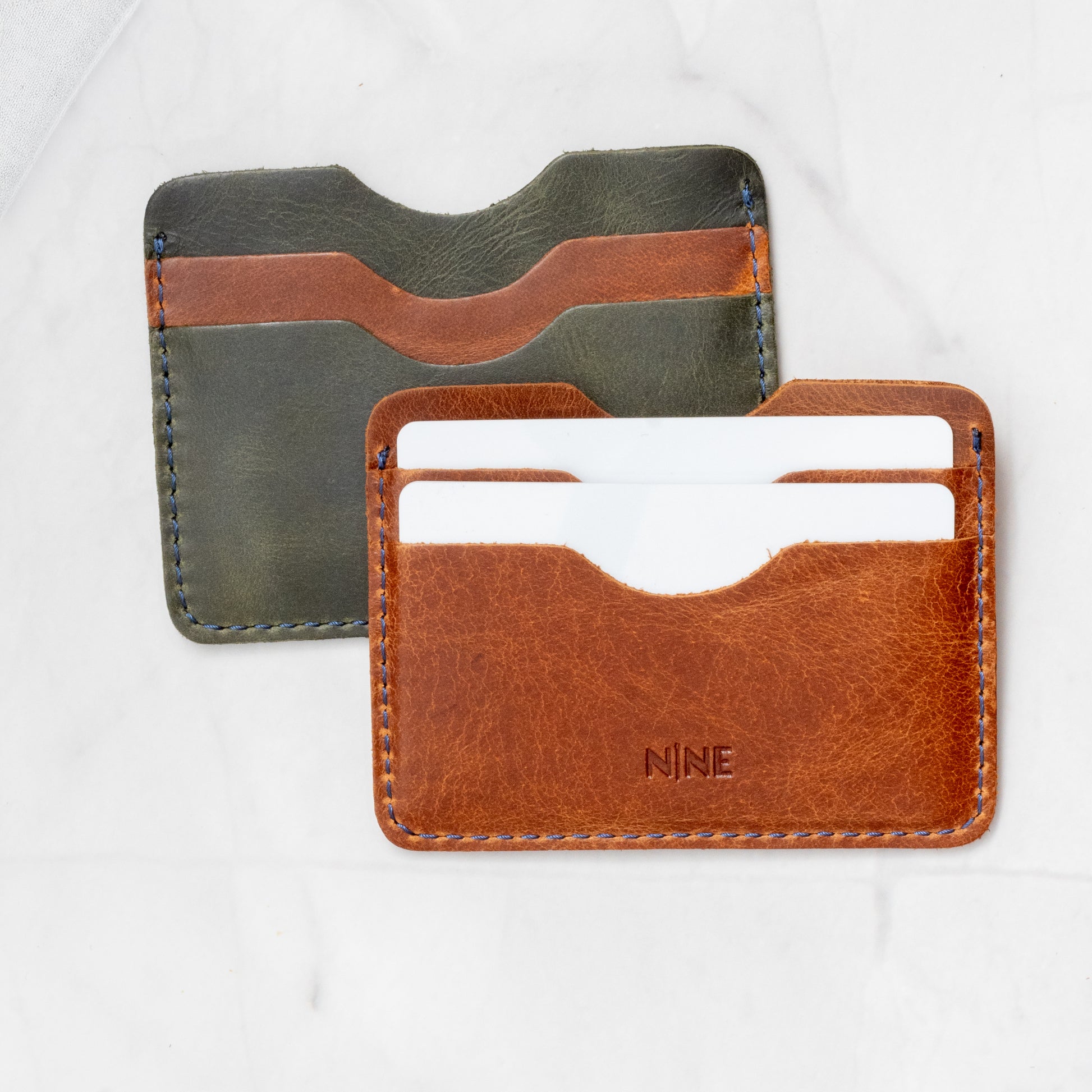 Tan and Olive Green Full-Grain Leather Compact Card Wallets layered, highlighting the 4-slot design and contrast stitching.