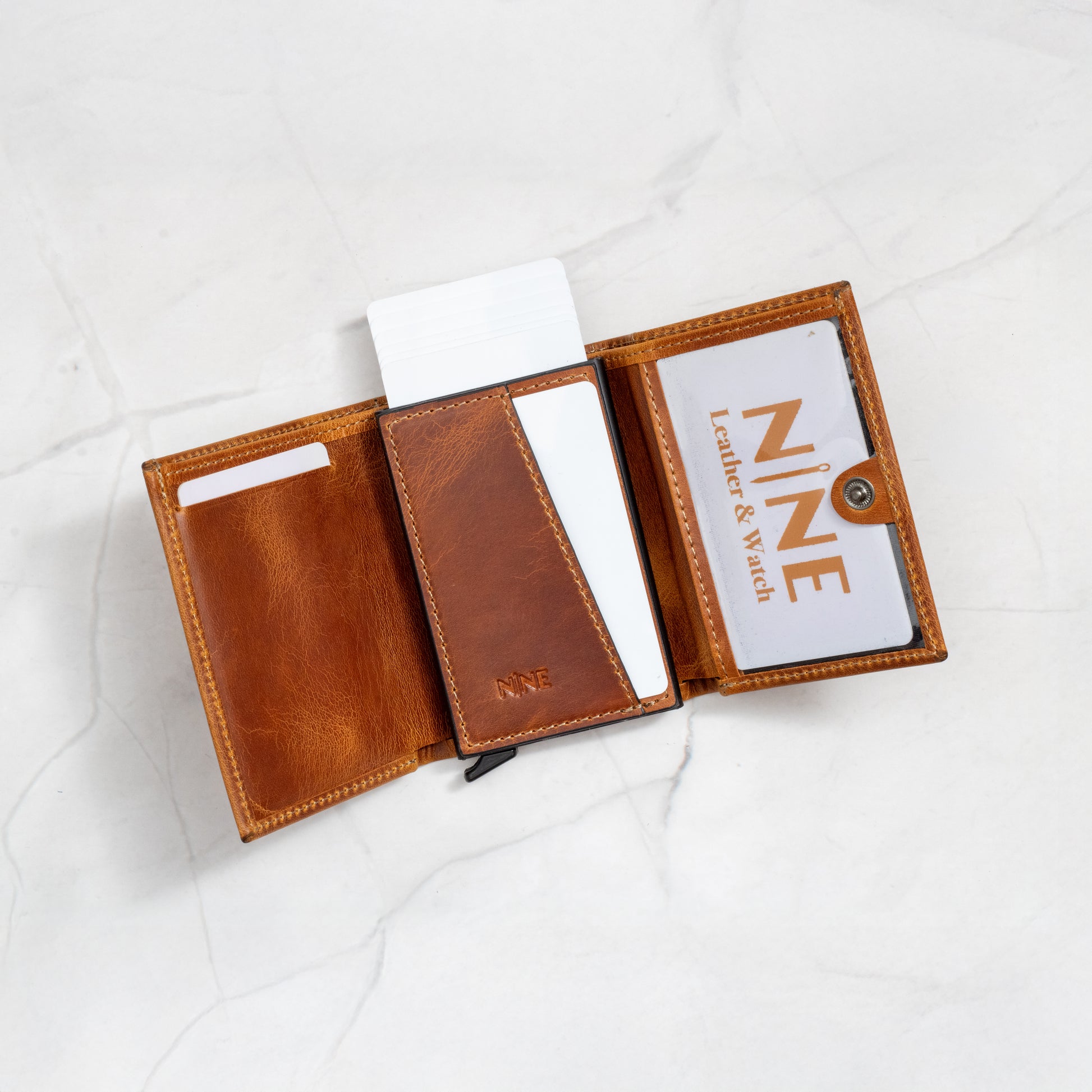 Tan Full-Grain Leather Pop-Up Trifold Wallet opened, showing the clear ID window, card pockets, and NINE branding.