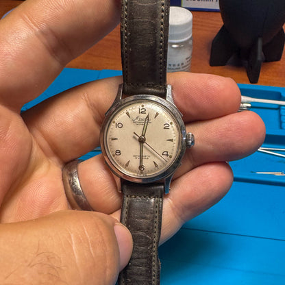 Full frontal view of a vintage 1940s Minerva men's mechanical watch resting in a hand, showing the case and dial proportions.