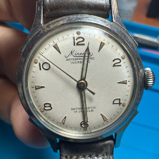 Close-up of a vintage 1940s Minerva mechanical watch dial showing its authentic patina, original hands, and Incabloc text