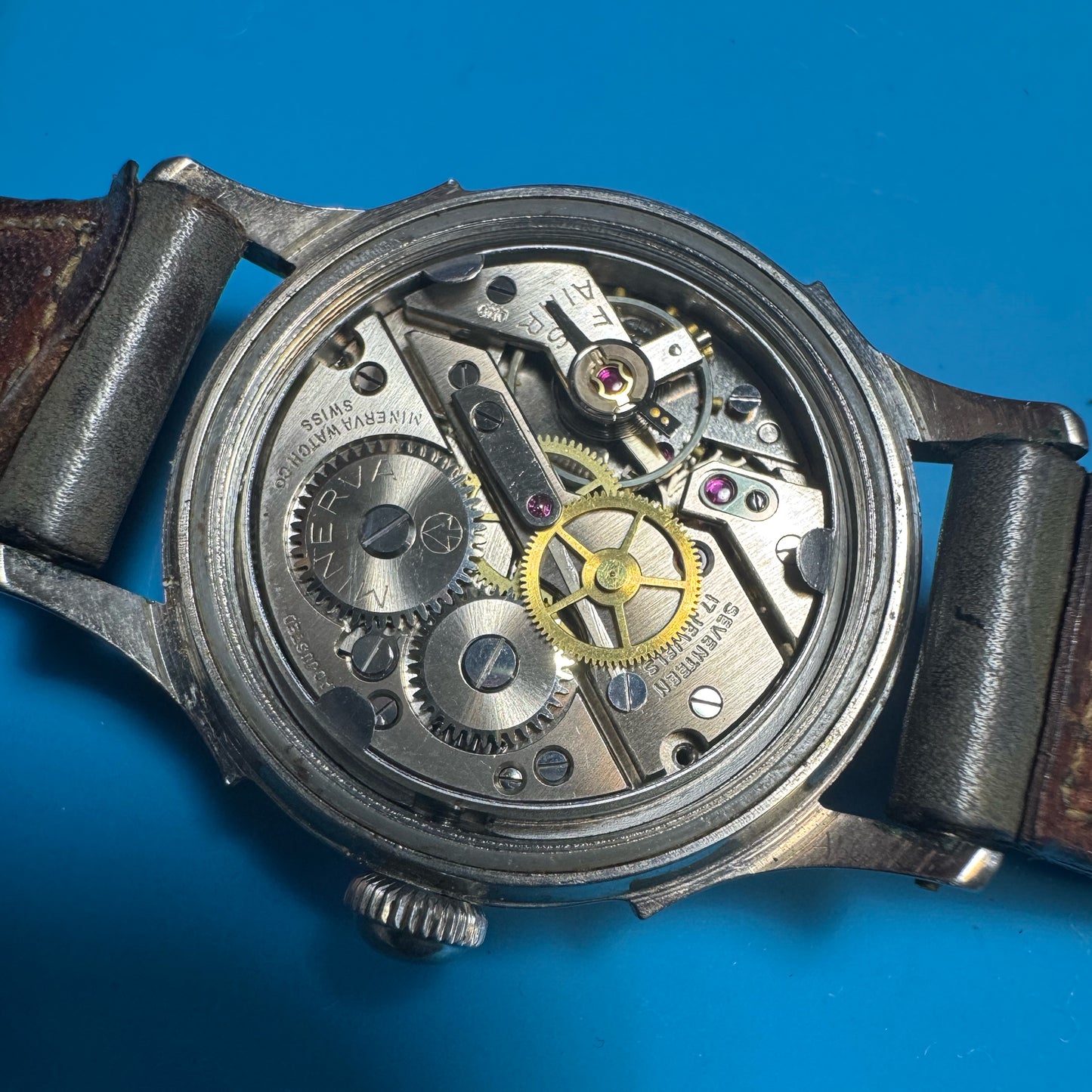 Open case back of a vintage Minerva watch revealing the clean, 17-jewel Swiss mechanical hand-winding movement.