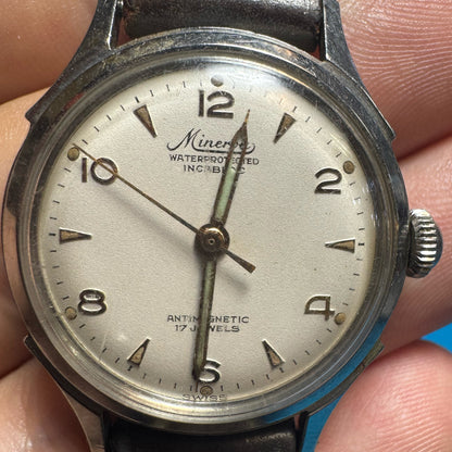 Clear, straight-on close-up of a vintage 1940s Minerva watch dial displaying Arabic numerals, syringe hands, and a beautiful vintage patina.