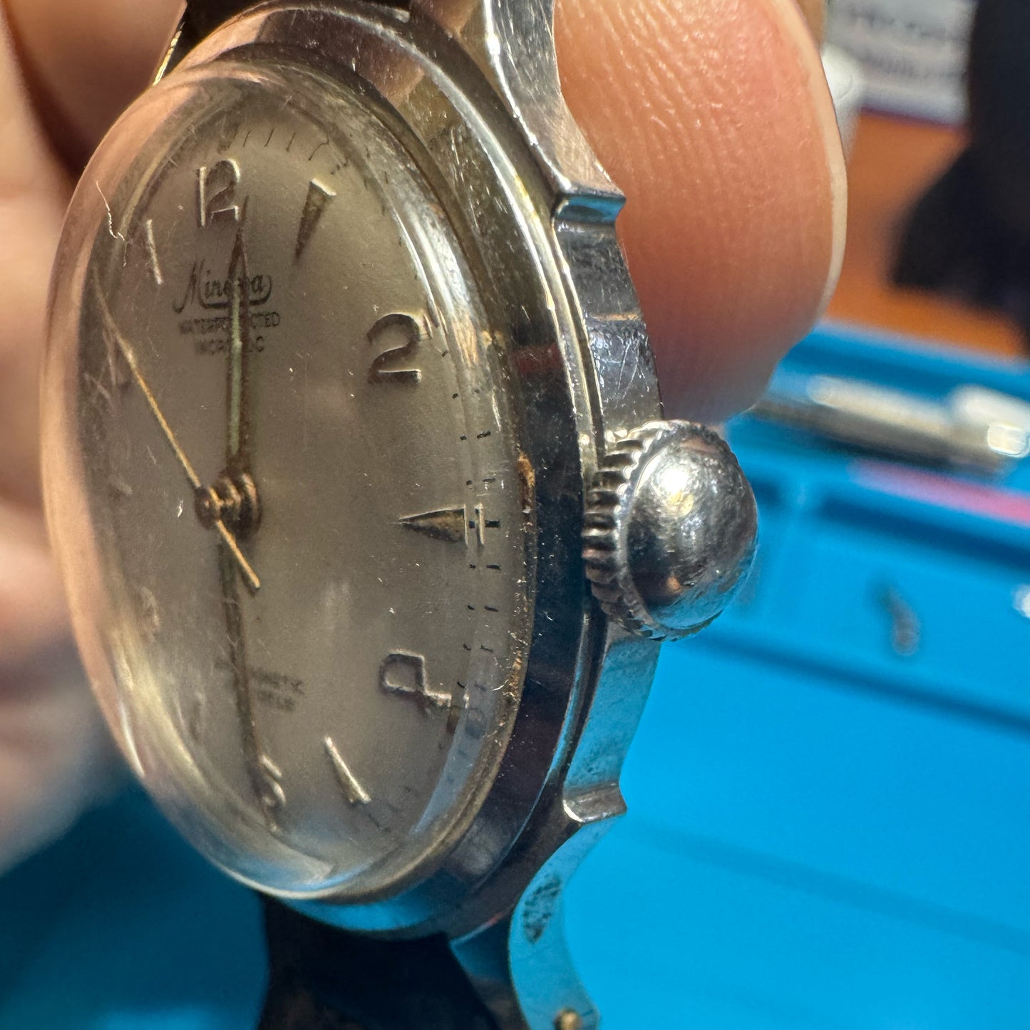 Side profile view of a vintage 1940s Minerva watch showcasing the polished stainless steel case, winding crown, and domed crystal
