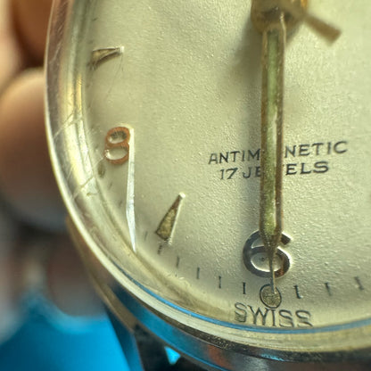 Extreme close-up of a vintage Minerva watch dial highlighting a stable micro-crack in the domed crystal near the 8 o'clock marker