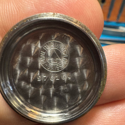 Inside view of a vintage Minerva watch case back featuring engine-turned decoration, the Minerva Watch Co. logo, and serial number 976164