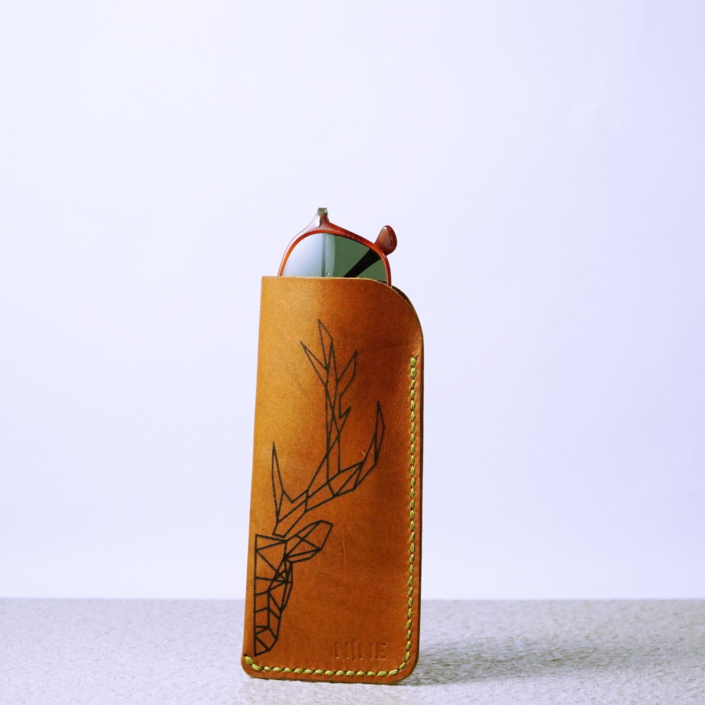 A brown leather sunglasses case with a pair of sunglasses inside, showcasing its slim profile and protective design.